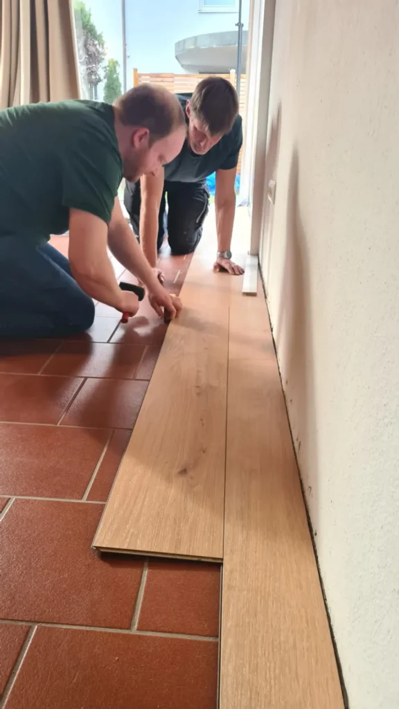 Zwei Männer verlegen Parkettboden in einem Haus
